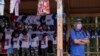 Un hombre espera un autobús de transporte público junto a un puesto que vende camisetas, banderas y gorras, con un tema sandinista, en una parada de autobús en Managua, Nicaragua, el miércoles 3 de noviembre de 2021. Foto AP/Andrés Núñez
