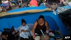 Solicitantes de asilo preparan comida mientras esperan que las autoridades estadounidenses les permitan comenzar su proceso de migración. México, el 14 de abril de 2021.