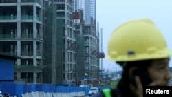 Seorang pekerja sedang berbicara melalui ponsel di lokasi proyek real estat Meikarta, di Cikarang, Bekasi,15 Oktober 2018. (Foto: Antara Foto/Risky Andrianto via Reuters)