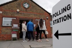 People queue at the entrance of a polling station in London, May 6, 2021. Millions of people across Britain cast ballots Thursday, in local elections, the biggest set of votes since the 2019 general election.