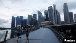 Para pelari berolahraga di dekat Merlion Park di Singapura saat negara kota membuka kembali perekonomian di tengah wabah COVID-19, 19 Juni 2020. (Foto: REUTERS/Edgar Su)