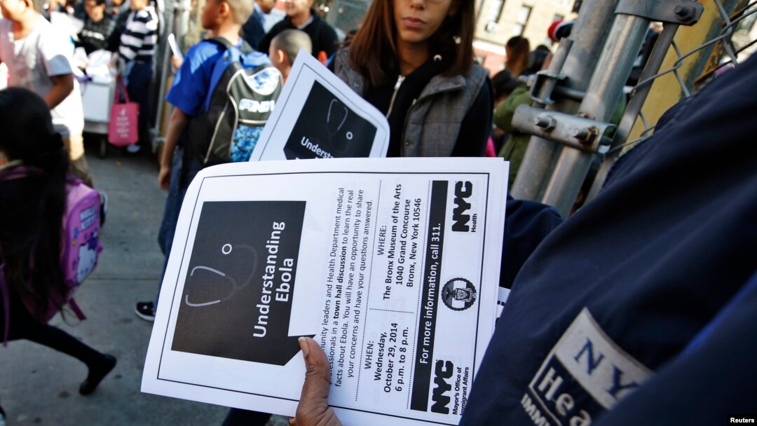 FILE - A New York City Health department official hands out information on the Ebola virus outside a school near a Bronx New York apartment building, Oct. 27, 2014.