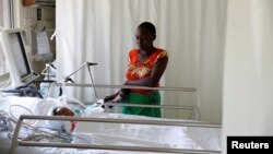 FILE - Lenzer, mother of six month-old Samantha Pendo, stands next to her bed as the girl remains in critical condition in the Intensive Care Unit of Aga Khan Hospital in Kisumu, Kenya, August 14, 2017. 