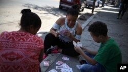 Dunea Romero of Honduras plays cards with her son and a friend from El Salvador outside the migrant shelter where they are staying while waiting to hear whether they will be granted U.S. asylum, in Tijuana, Mexico, Sept. 12, 2019.