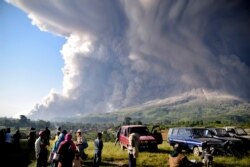 Warga menyaksikan Gunung Sinabung memuntahkan abu vulkanik saat meletus di Karo, Sumatera Utara, Selasa, 2 Maret 2021. (Foto: Ilustrasi/AP).