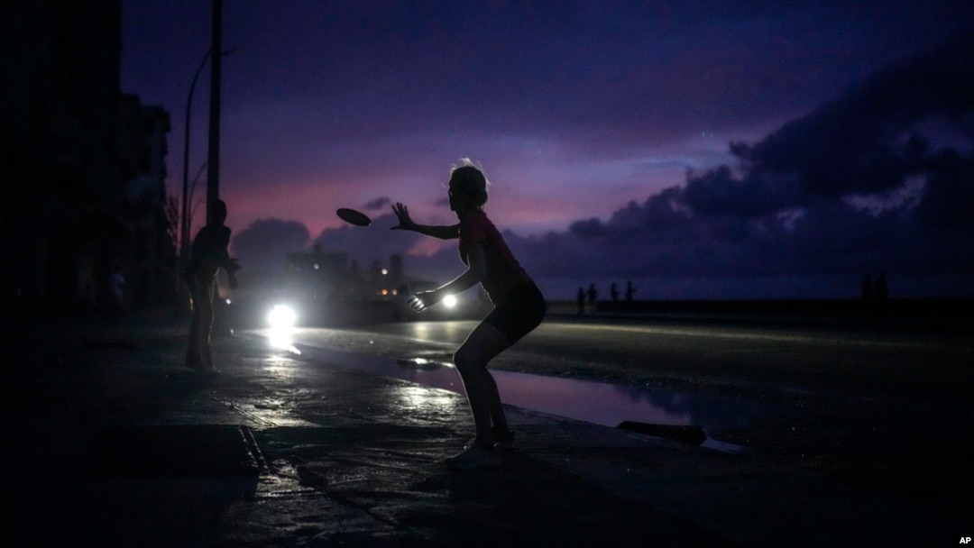 A woman prepares to catch a tossed flying disc during a massive blackout after a major power plant failed in Havana, Oct. 18, 2024.