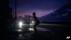 A woman prepares to catch a tossed flying disc during a massive blackout after a major power plant failed in Havana, Oct. 18, 2024.