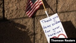 A note and U.S flag are shown placed at the main gate to U.S. Marine Base Camp Pendleton in Oceanside, California