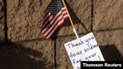 Following the deadly bombing at Hamid Karzai International Airport in Kabul, Afghanistan, a note and US flag are shown placed at the main gate to US Marine Base Camp Pendleton in Oceanside, Calif., Aug. 27, 2021.