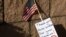 Following the deadly bombing at Hamid Karzai International Airport in Kabul, Afghanistan, a note and US flag are shown placed at the main gate to US Marine Base Camp Pendleton in Oceanside, Calif., Aug. 27, 2021.