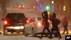 Pedestrians cross a snowy street in downtown Kansas City, Mo., Dec. 17, 2016. A winter storm of snow, freezing rain and bone-chilling temperatures hit the nation's midsection and East Coast on Saturday.