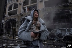 Ivanna holds her dog in front of a burning car after a Russian attack in Kyiv, Ukraine, Dec. 20, 2024.