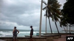 Los hombres miran el mar durante la presencia de la tormenta Isaías en Santo Domingo, el 30 de julio de 2020.