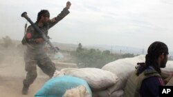 An Afghan National Army soldier, left, shouts against the Taliban, after firing a rocket toward Taliban positions, on the outskirts of Kunduz, northern Afghanistan, April 16, 2016. 