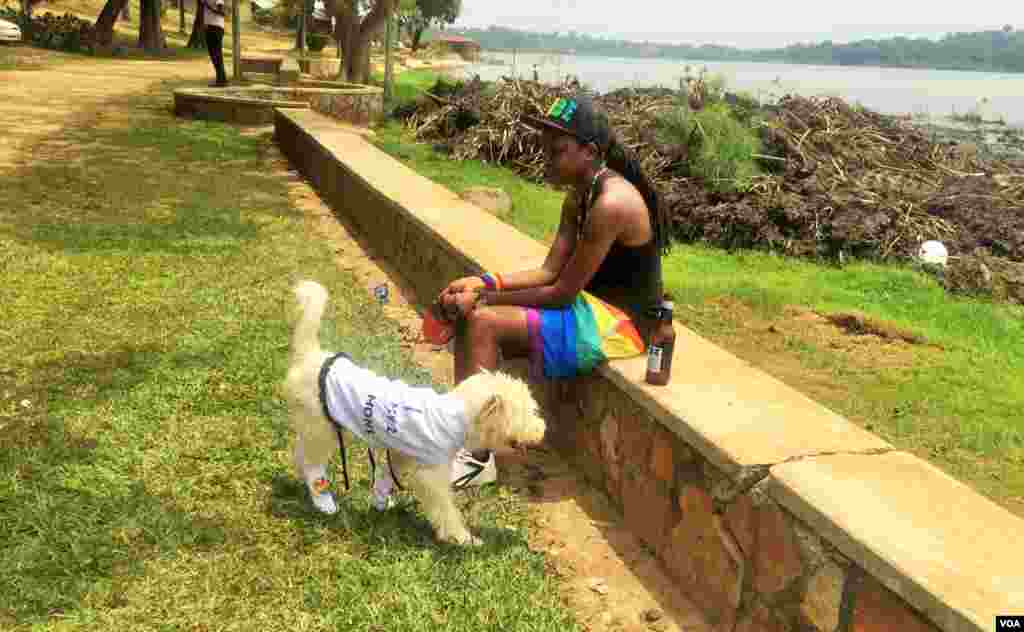 Activist Kasha Jacqueline Nabagesera sat quietly with her dog, refusing to leave, as police made preparations to tow her vehicle. (L. Paulat/VOA)