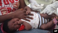 A child is vaccinated by a health worker at the Pipeline Community Health Center, situated on the outskirts of Monrovia, Liberia, on November 3, 2014. 