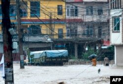 Nepali residents walk through floodwaters after the Balkhu River overflowed following monsoon rains at the Kalanki area of Kathmandu, July 12, 2019.