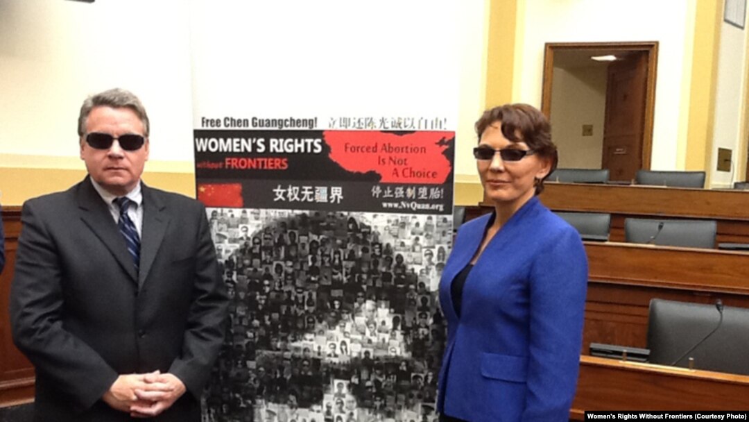 女權無疆界組織負責人瑞潔在國會作證後，同眾議員史密斯帶黑眼鏡在陳光誠巨幅相片前留影聲援陳光誠