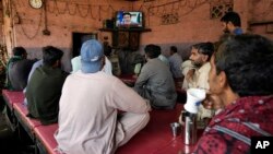 People watch a TV news report about the death of former Pakistani President Gen. Pervez Musharraf at a coffee shop in Karachi, Pakistan, Feb. 5, 2023. 