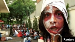 Seorang aktivis pelajar Indonesia mengikat mulutnya untuk melambangkan kurangnya kebebasan berbicara saat melakukan protes di depan kantor Komisi Hak Asasi Manusia di Jakarta Pusat. (Foto: Reuters)