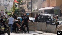 Supporters of a Shiite group allied with Hezbollah help an injured comrade during armed clashes that erupted during a protest in the southern Beirut suburb of Dahiyeh, Lebanon, Oct. 14, 2021.