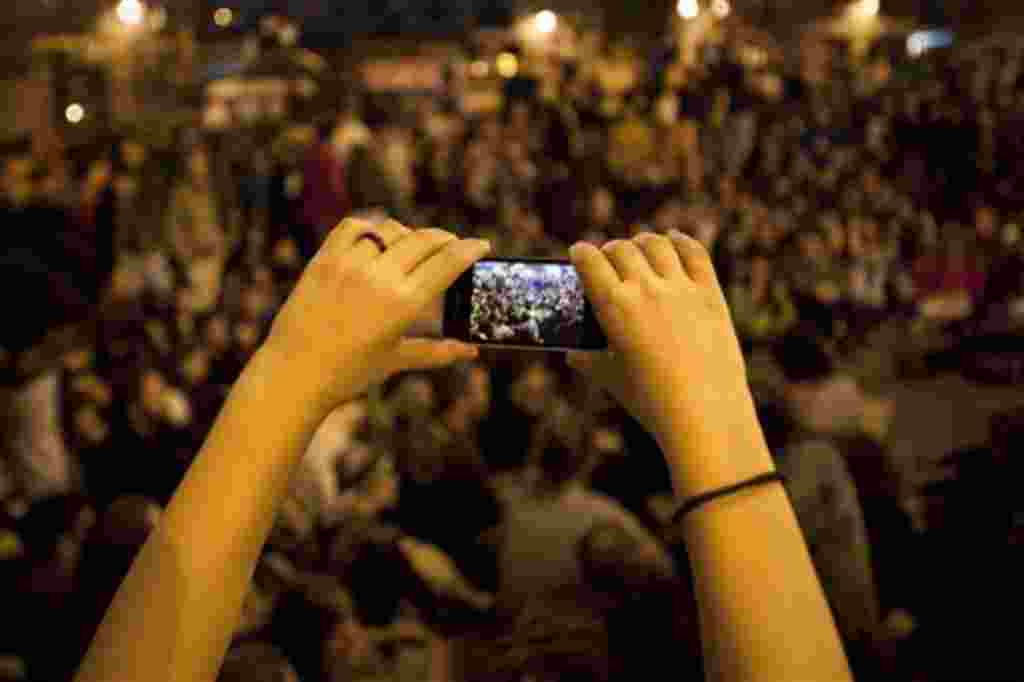 Una mujer toma fotografías con su cámara durante una manifestación en Madrid, 18 de mayo 2011.