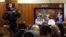 A bailiff stands in a room as people watch a live broadcast of a court hearing on members of the female punk band 'Pussy Riot' in Moscow October 10, 2012.