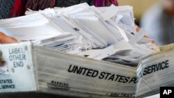 A election worker moves a tray of ballots as vote counting in the general election continues at State Farm Arena in Atlanta, Nov. 5, 2020.