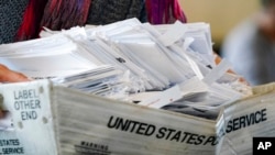 A election worker moves a tray of ballots as vote counting in the general election continues at State Farm Arena in Atlanta, Nov. 5, 2020.