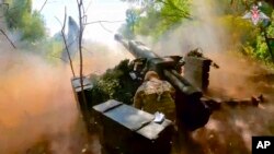 Dalam foto yang diambil dari video yang dirilis oleh Kementerian Pertahanan Rusia pada 7 Agustus 2024, tentara Rusia melepaskan tembakan dari howitzer D-30 ke arah posisi Ukraina di lokasi yang dirahasiakan di Ukraina. (Layanan Pers Kementerian Pertahanan Rusia via AP)