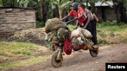 People ride with their belongings on a wooden bicycle as they flee from renewed fighting between Congolese army and M23 rebels near the eastern Congolese city of Goma, July 24, 2012.