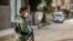 FILE - A member of the Kurdish Internal Security Forces of Asayesh stands guard on a deserted street in Syria's northeastern city of Hasakah.