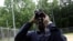FILE - Keith Russell, program manager of urban conservation at Audubon Pennsylvania, looks through binoculars while conducting a breeding bird census, at Wissahickon Valley Park, June 5, 2020 in Philadelphia. 
