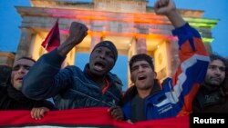 Refugees shout slogans during a protest by asylum seekers calling for fairer treatment from authorities as they pass through Brandenburg Gate in Berlin, October 13, 2012. 