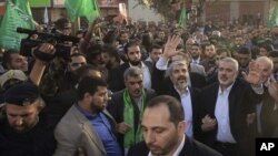 The exiled Hamas chief, Khaled Meshaal (L), and Gaza's Hamas prime minister, Ismail Haniyeh, wave as they parade through the streets following Meshaal's arrival in Gaza City December 7, 2012.