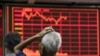 FILE - An investor looks at an electronic board showing stock information at a brokerage house in Beijing, China, Aug. 27, 2015. 