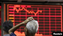 FILE - An investor looks at an electronic board showing stock information at a brokerage house in Beijing, China, Aug. 27, 2015. 