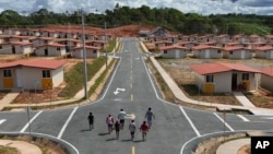 Residentes de la isla de Gardi Sugdub caminan hacia sus nuevos hogares en el continente en Nuevo Cartí, en la costa caribeña de Panamá, el miércoles 5 de junio de 2024.