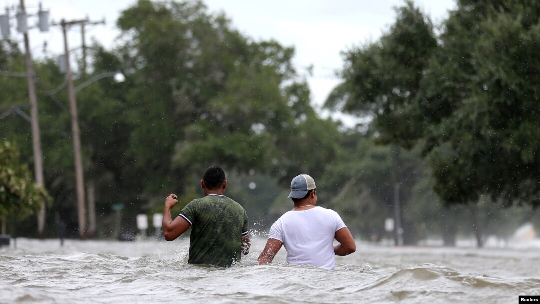 Dos hombres caminan por una calle inundada tras el paso del huracán Barry en Mandeville, Louisiana, EE.UU., el sábado,13 de julio de 2019. 