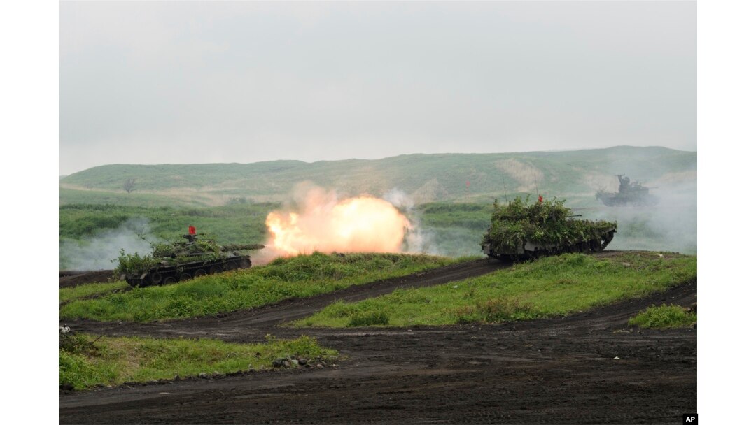 Tank Tipe-74 Pasukan Bela Diri Darat Jepang (JGSDF), kiri, menembakkan amunisi selama latihan tembakan di Area Manuver Fuji Timur di Gotemba, barat daya Tokyo, Sabtu, 22 Mei 2021. (Foto: via AP)