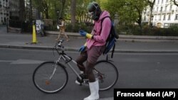 In this April 20, 2020 file photo, a delivery man, who want to name Moise, wearing protective gear checks his phones during a nationwide confinement in Paris. (AP Photo/Francois Mori, File)