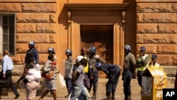 Policemen keep an eye on pedestrians passing by, in Bulawayo, Zimbabwe, Monday, Aug. 19, 2019. Few people turned up for an opposition protest Monday in the Zimbabwe's second city as armed police maintained a heavy presence on the streets. (AP Photo…