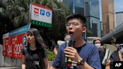 Aktivis prodemokrasi Hong Kong, Joshua Wong (kanan) dan Agnes Chow (kiri) berjalan menuju markas polisi di Hong Kong, 21 Juni 2019.