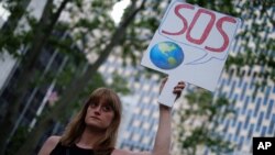 A woman displays a placard during a demonstration in New York on June 1, 2017, to protest US President Donald Trump's decision to pull out of the 195-nation Paris climate accord deal. 