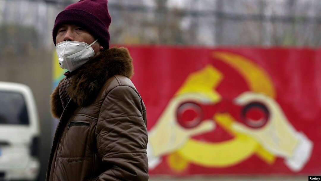 Arhiva - Čovjek nosi masku ispred murala na kome je predstavljena modifikovan amblem vladajuće Komunističke partije Kine, tokom izbijanja epidemije koronavirusa, 28. januara 2020. (REUTERS/Aly Song)