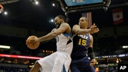 Ronny Turiaf, à gauche, des Minnesota Timberwolves aux prises avec Derrick Favors des Utah Jazz lors d'un match de la NBA à Minneapolis en 2014.