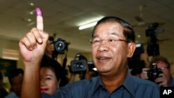 FILE PHOTO - Cambodia's Prime Minister Hun Sen, foreground, shows his inked finger after voting at a polling station in Takhmau town, south of Phnom Penh, Cambodia, Sunday, July 28, 2013. Hun Sen was among the early voters Sunday, casting his ballot shortly after the polls opened in a national election his party is expected to easily dominate. (AP Photo/Heng Sinith)