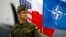 FILE - A Polish soldier stands in front of U.S., Polish and NATO flags ahead of military exercises in Swidwin, northwestern Poland, April 23, 2014.
