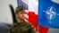 FILE - A Polish soldier stands in front of U.S., Polish and NATO flags ahead of military exercises in Swidwin, northwestern Poland, April 23, 2014.