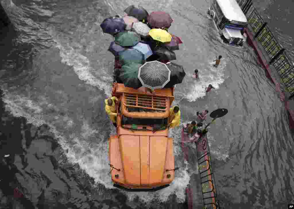 A truckload of stranded commuters cross a flooded street in Manila, Philippines. 